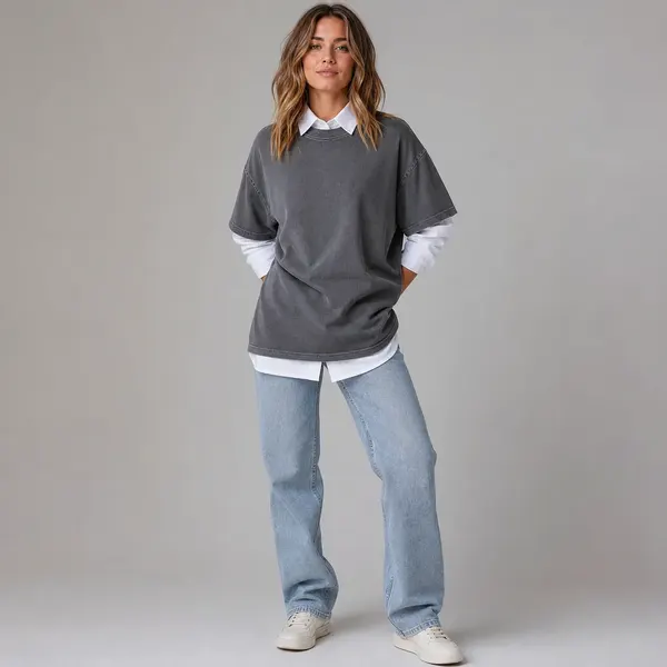 Woman wearing an oversized grey T-shirt over a white shirt and jeans